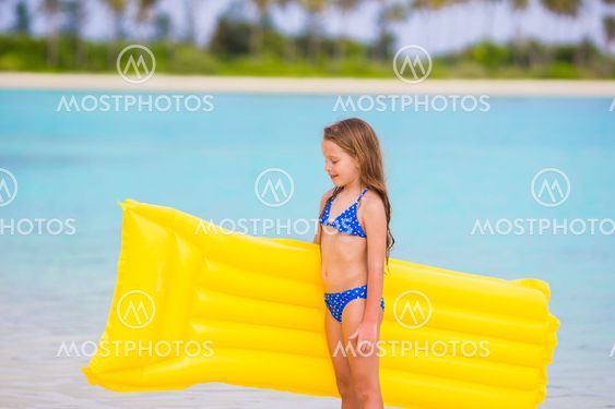 Adorable little girl with air inflatable mattress during...