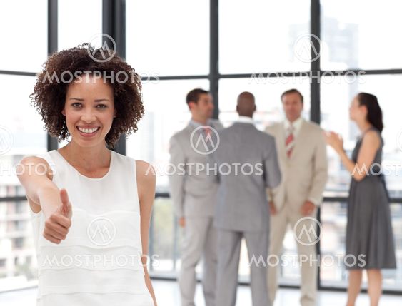 Bright Businesswoman doing a thum-up with his colleagues