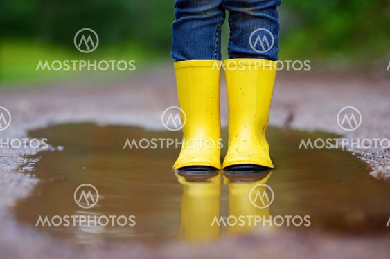 Child wearing rain boots standing in a puddle