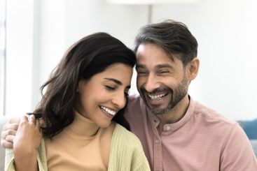 Beautiful multiethnic couple in love sit close together...