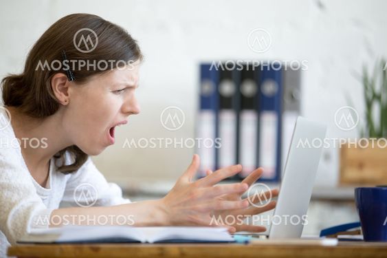 Young business woman screaming at laptop