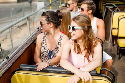 group of smiling friends traveling by tour bus