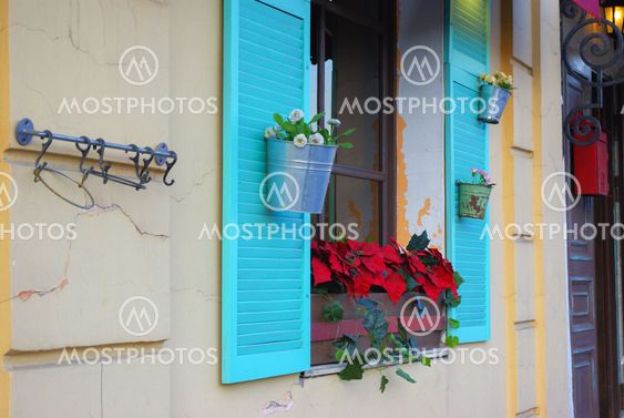 white stone facade with blue shutters and flowers from the side