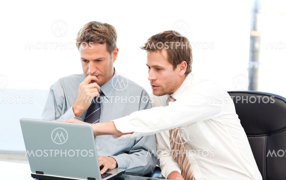 Two handsome businessmen working together on a project sitting at a table
