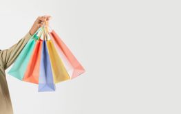 Elderly man holding colorful shopping bags on white...
