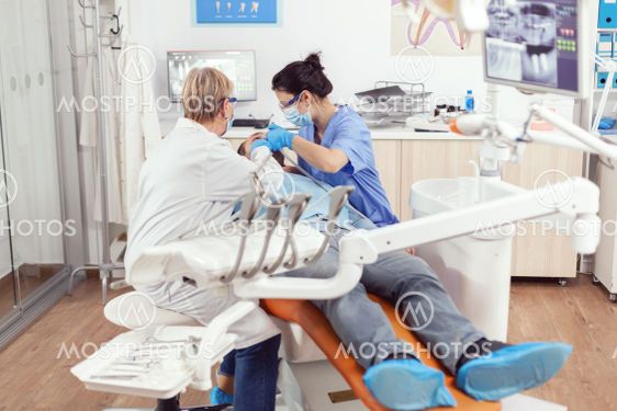 Sick man lying on stomatological chair while senior...
