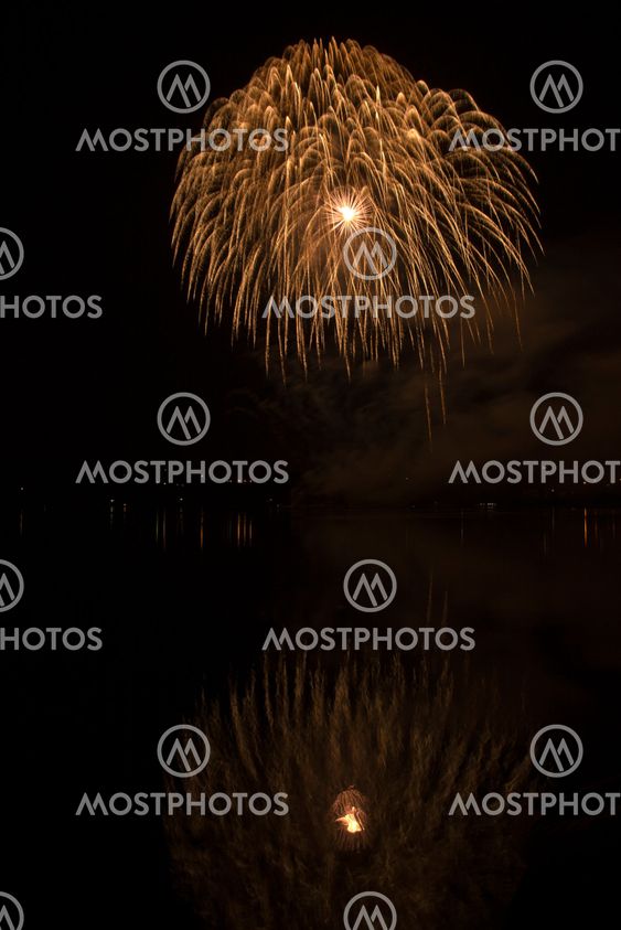 Colorful fireworks on the black sky background and water reflections