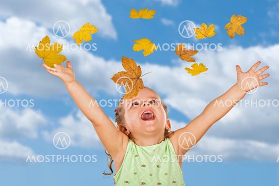 Happy shouting little girl with falling autumn leaves