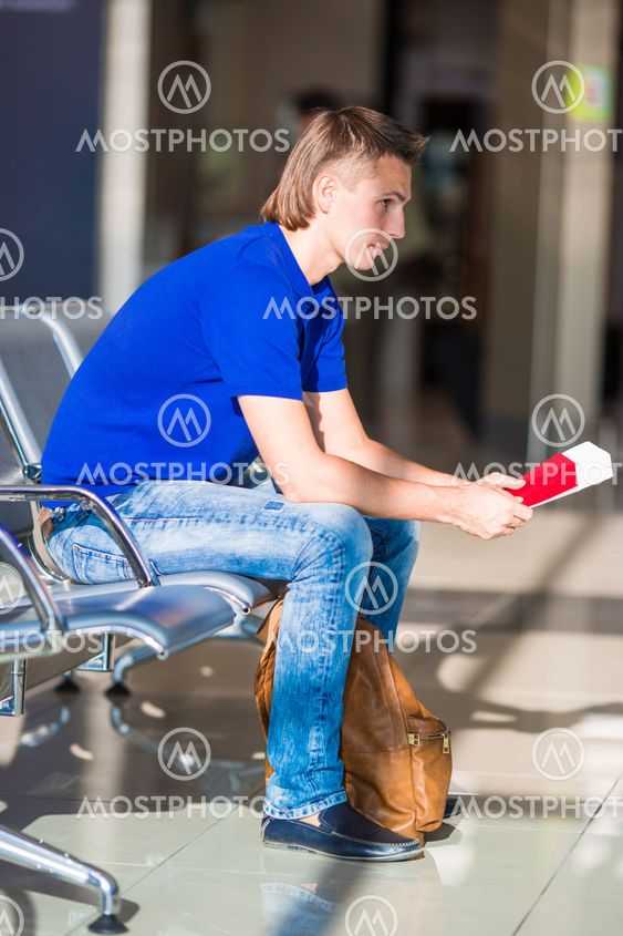 Young man holding passports and boarding pass at airport