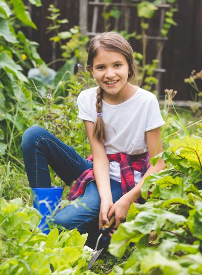 Smiling girl working at garden and digging out fresh...