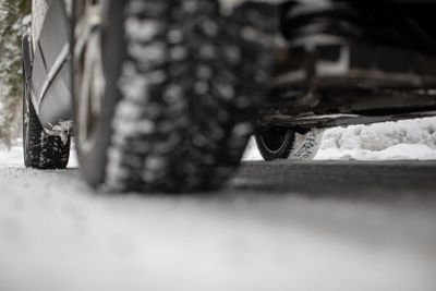 Car on a snowy winter road amid forests - using its four...