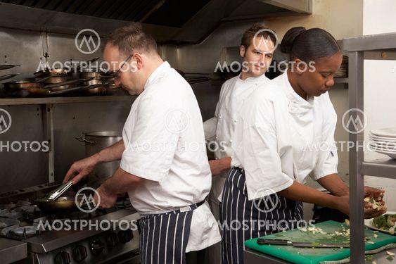 Team Of Chefs Preparing Food In Restaurant Kitchen