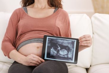 Home, woman and hands with pregnancy scan on sofa in...