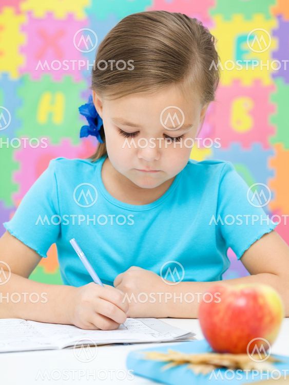Little girl is writing using a pen