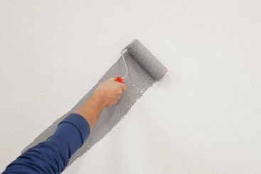 hand with paint roller in hand, painting a wall