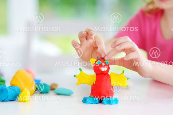 Cute little girl having fun with colorful modeling clay...