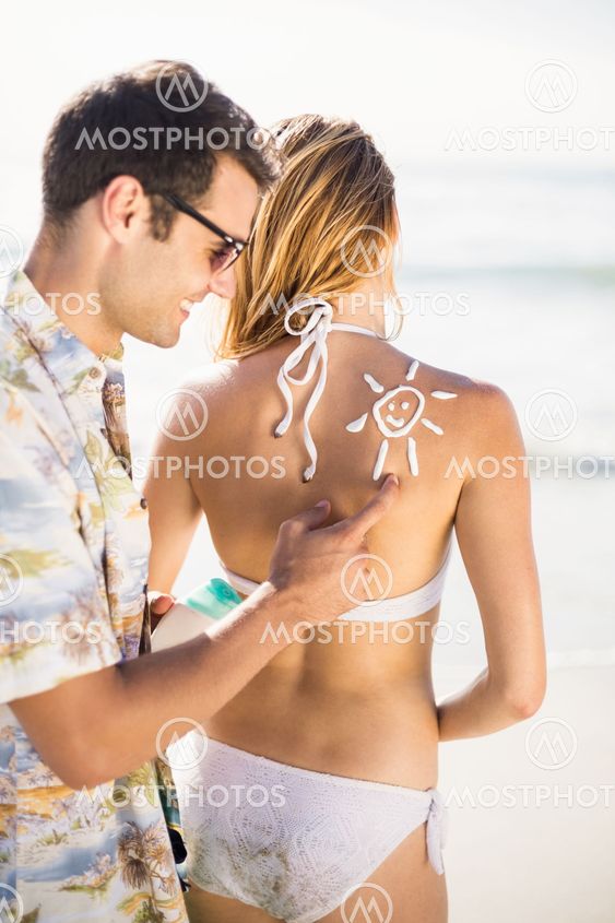 Man making a sun symbol on womans back while applying a...
