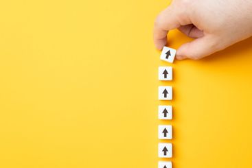 Hand making a row of arrows on a yellow background....