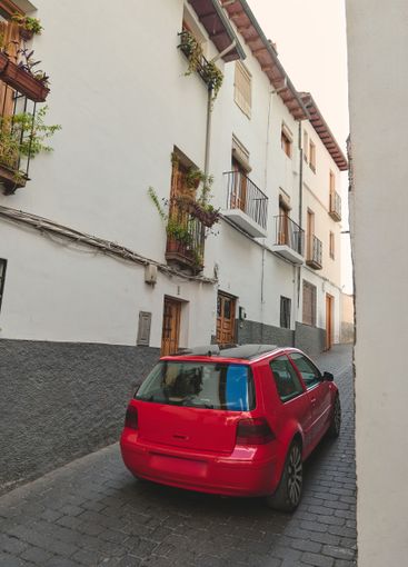 Red compact car parked on a narrow charming European street