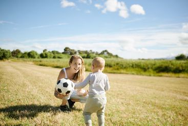 Baby, soccer ball and a mother playing with her son on a...