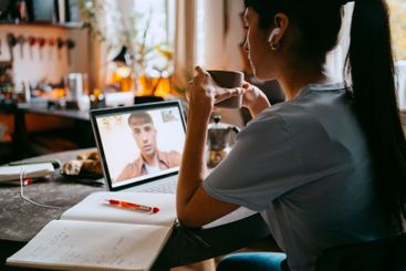 Young female freelancer holding coffee cup while doing...