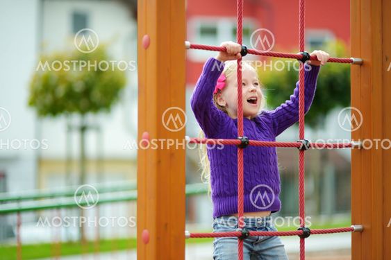Cute little girl having fun on a playground outdoors in...