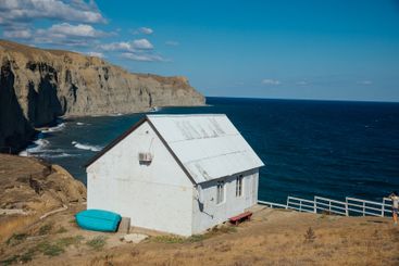 House with a boat on a cliff on seashore