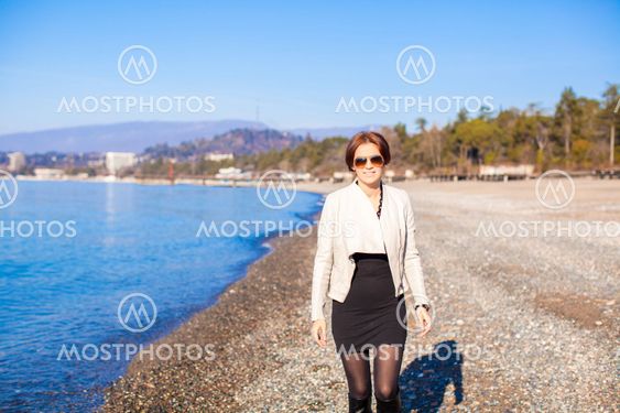 Beautiful young woman walking on the beach in winter sunny day alone