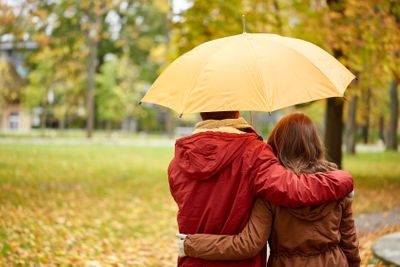 happy couple with umbrella walking in autumn park