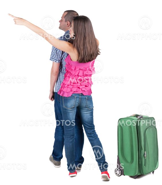 young couple traveling with suitcas and pointing at wal...