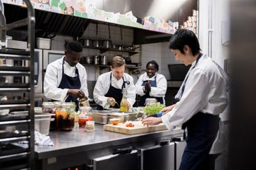 Multiracial chefs working in commercial kitchen at...