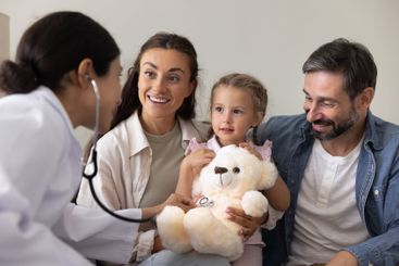 Young Indian doctor examining little kid sitting on...