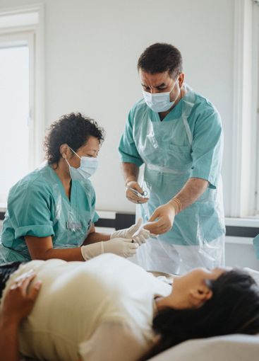 Male and female surgeons operating young woman in hospital