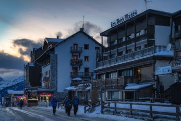 A charming snowy village street at dusk features...