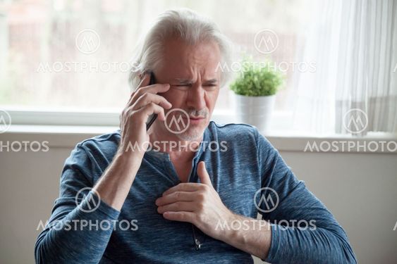 Stressed senior man having heart attack while talking on phone