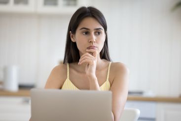 Young lady distracted from work on notebook with pensive...