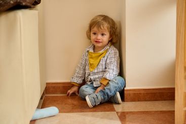 Adorable Young Child Seated in a Cozy Indoor Corner...
