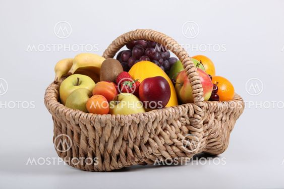 Wicker basket full of fresh fruit at a slight angle