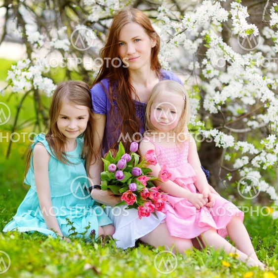 Mother and her children in blooming cherry garden