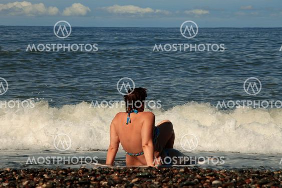 Woman sitting on shore of the sea on the beach