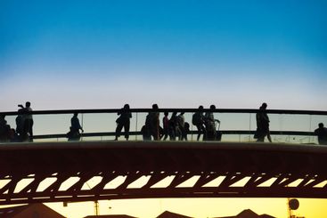 Silhouette of walking people on bridge