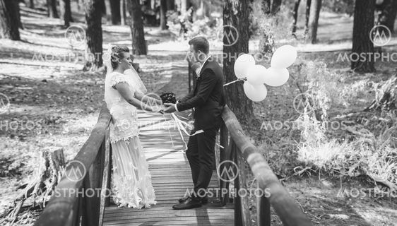 Black and white photo of happy bride and groom holding...