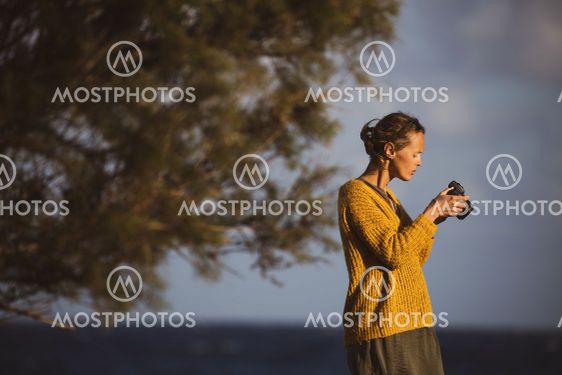 Pretty, young woman with a mirrorless camera, taking...
