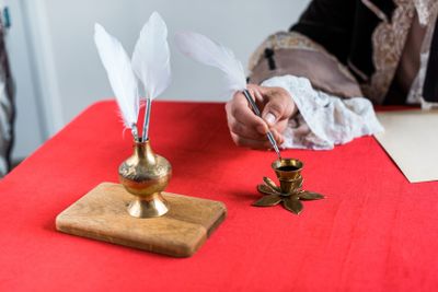cropped view of victorian man holding feather near ink...