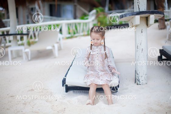 adorable little girl on the beach playing with sand