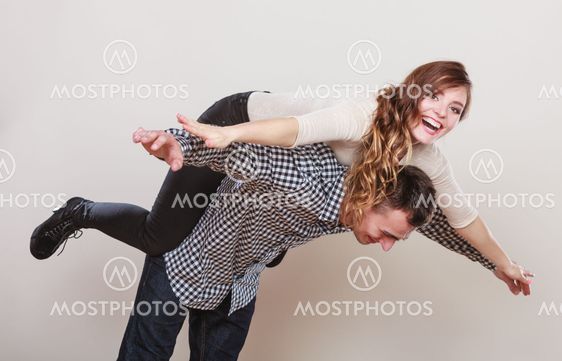 Woman riding piggyback on man. Happy couple.
