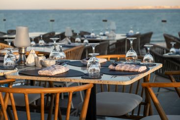 Elegant seaside dining setup with glassware, overlooking...