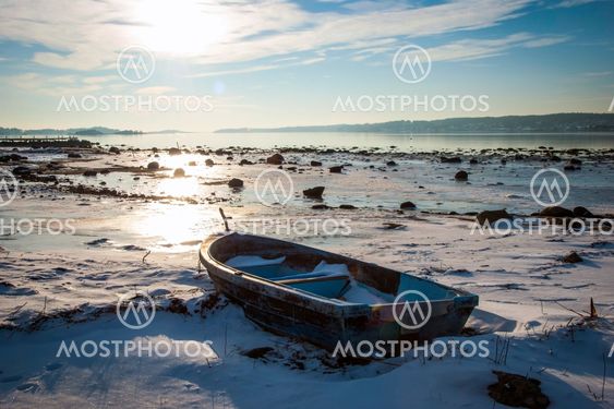 Boat frozen in fjord in winter sunshine