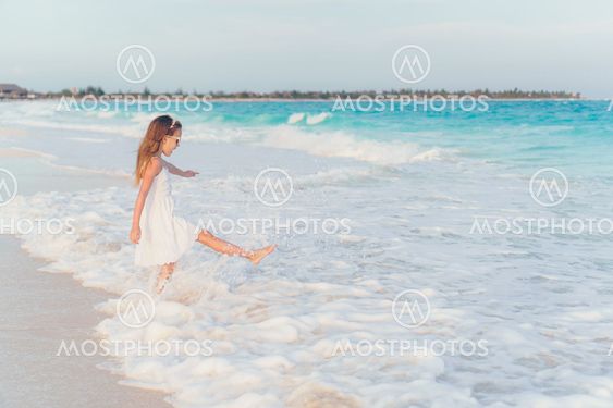 Adorable little girl at beach having a lot of fun in...