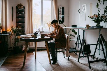 Freelancer working on laptop while sitting on chair at...